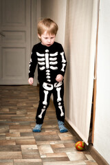 A child in a skeleton costume plays football in the hallway of the house - 508177257