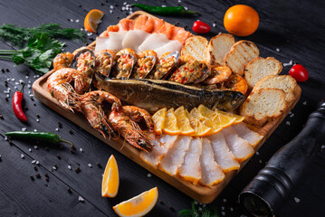 assorted fish cuts, shrimp, bread. on a black wooden background