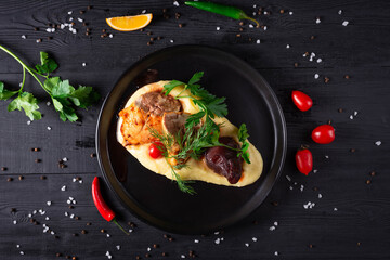 turkey with pear and mashed potatoes with herbs and tomatoes on a black wooden background