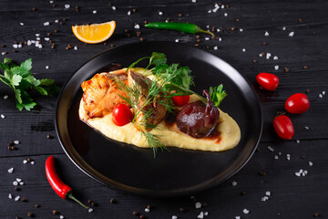 turkey with pear and mashed potatoes with herbs and tomatoes on a black wooden background