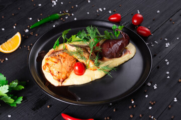 turkey with pear and mashed potatoes with herbs and tomatoes on a black wooden background