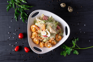 salad of shrimp, vegetables and quail eggs on a black wooden background