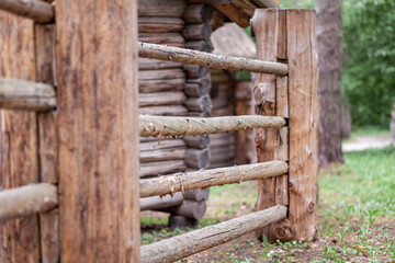 Large wooden fence posts that enclose an old wooden house in the forest. How people built houses...