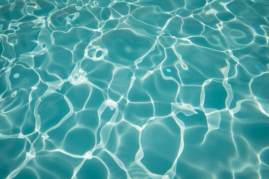 abstract turquoise water background of swimming pool with waves and light reflection
