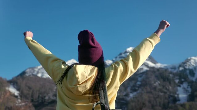 Winner backpacker female celebrating victory freedom independence at mountain snowy peak back view