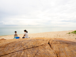 Empty wooden log with blur beach, child and mother on background. Used for product placement.