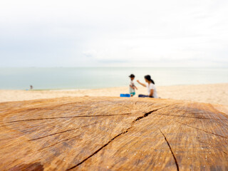 Empty wooden log with blur beach, child and mother on background. Used for product placement.