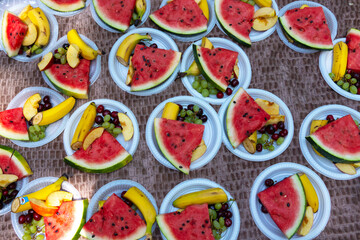 watermelon and other fruits on plates in the park