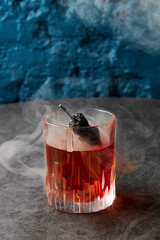 Alcohol cocktail with dry hot pepper in smoke on stone table