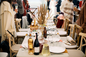 Guests holding drinks stand at served table having party