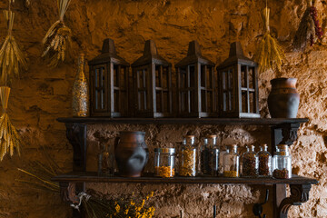 Vintage rack with lanterns and bottles on rough stone wall