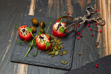 Tomatoes stuffed with cheese cream served on slate plate