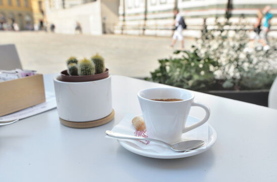 cup of coffee on a table in terrace with a potted plant in the square of Duomo in Firenze