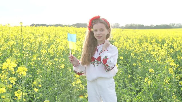 Pray for Ukraine. Child with Ukrainian flag in rapeseed field. Little girl holding national flag in her hand. Happy kid celebrating Independence Day.