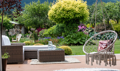 Fototapeta premium Huśtawka na tarasie w pięknym ogrodzie . Miejsce wypoczynku i relaksu w ogrodzie
