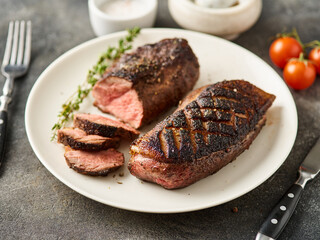 Juicy tasty fragrant roasted duck breast on a white plate with peppers and cherry tomatoes.