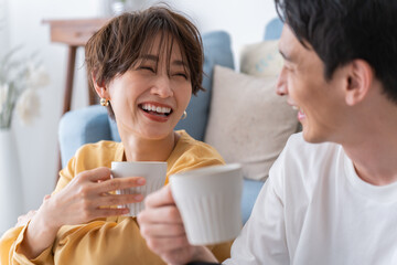部屋でくつろぎながら笑う仲良し若い日本人カップル・夫婦