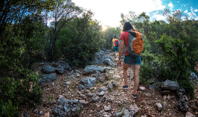 Two girls with a backpack walk along a mountain road