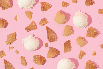 Summer creative layout with broken ice cream cone pieces and ice cream scoops on pastel pink...