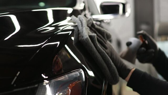 Man at car service doing car ceramic coating and polishes car with micro fiber