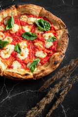 Traditional pizza margarita with tomatoes and mozzarella fried in the oven with a crispy crust on a...