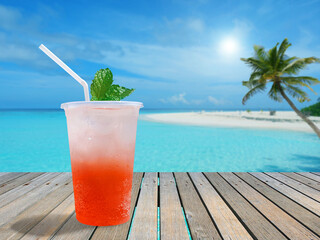 A glass of iced strawberry soda on a wooden terrace by the sea in sunny day with copy space for summer drinks concept.