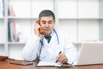 Doctor man at his desk talking on the phone