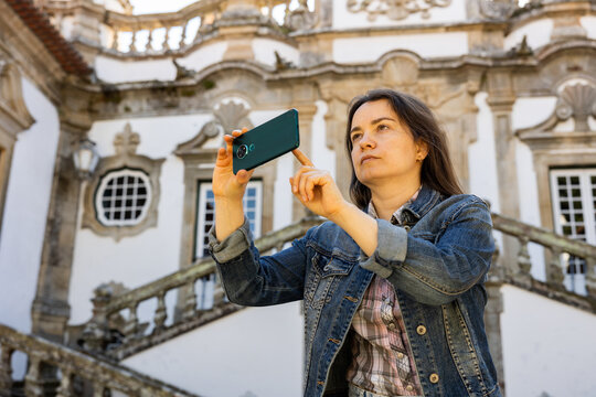 Woman taking pictures with her smartphone while standing at Mateus Palace in Vila Real, Portugal.
