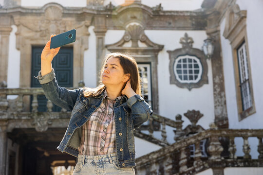Woman taking selfies with her smartphone near Mateus Palace, Vila Real, Portugal.