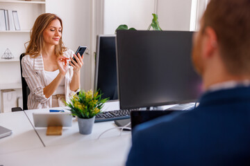Woman using smart phone while working in an office