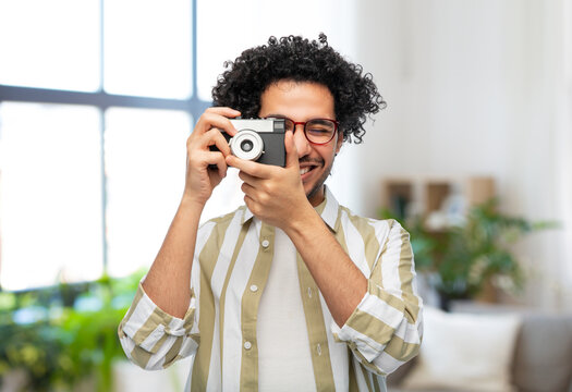 photography, hobby and people and concept - happy smiling man or photographer in glasses with film camera over home room background
