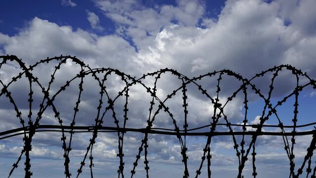 Сontour of barbed wire on background beautiful clouds and sky