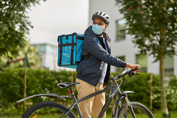 food shipping, health and people concept - delivery man in bike helmet and protective medical mask...