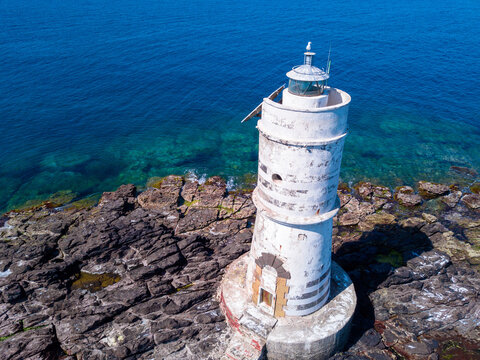 A White Lighthouse On A Sea Rock In An Aerial View