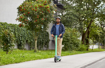 transport, safety and people and concept - young man in helmet riding electric scooter on city street © Syda Productions