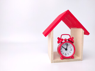 Alarm clock and toy house on a white background with copy space.