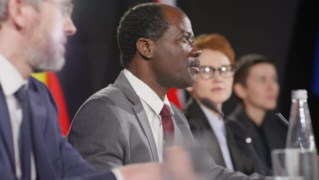 Selective focus shot of mature African American diplomat holding speech during international press conference