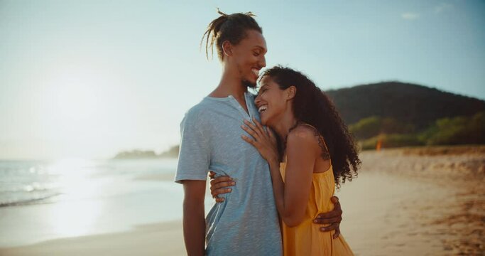 Happy black couple watching the sunset on the beach