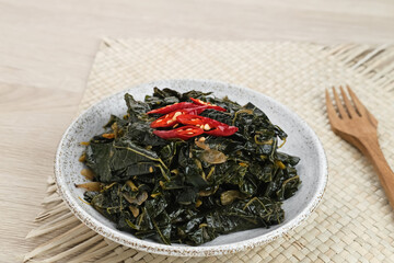 Stir Fry Papaya Leaves or Tumis Daun Pepaya, a traditional Indonesian dish made from boiled papaya leaves stir-fried with spices and chilies.
