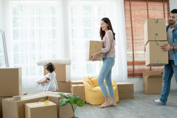 Latino father with beard, Asian mother and little cute daughter carrying packed cardboard boxes...
