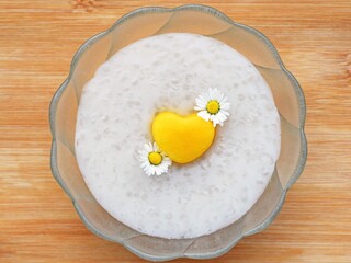 Homemade tapioca pudding with coconut milk, decorated with fresh nectarine in a shape of heart and edible daisy flowers. Romantic concept, inspiration