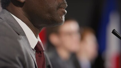 Cropped side view shot of African American man in formal suit speaking in mic during political press conference