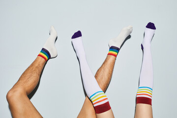 Vibrant shot of playful young couple wearing socks with rainbow symbols feet up against white wall