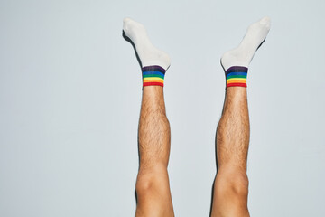 Minimal shot of young man wearing socks with rainbow symbols feet up, copy space