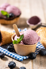 Blueberry ice cream scoops with waffle on wooden table	