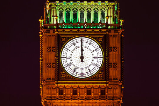 Big Ben of the Houses of Parliament London England UK at night striking midnight on new year's eve on Westminster Bridge which is a popular city landmark, stock photo image