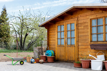 Small beautiful wooden house shed or storage hut for garden tools equipment and bicycles at backyard at beautiful american or european countryside backyard. Cozy rural yard stuff warehouse