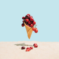 Ice cream cone filled with ripe cherries on the beach.  Fresh cherry in a waffle cone. Summer...