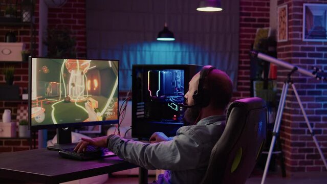 Man playing online first person shooter tournament congratulates team on headset after celebrating victory on gaming pc at home. Professional gamer winning competition doing victory hand gesture.
