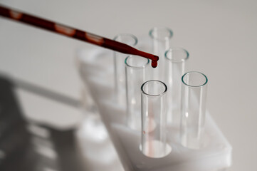 Close-up of a laboratory assistant dripping blood from a pipette into a test tube. 